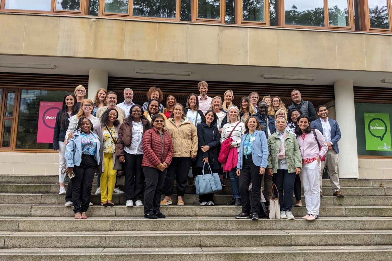 A group of INGO HR and Reward professionals stands on steps outside the University of Edinburgh’s Business School during the inaugural INGO Reward Conference, organised by Project Fair.