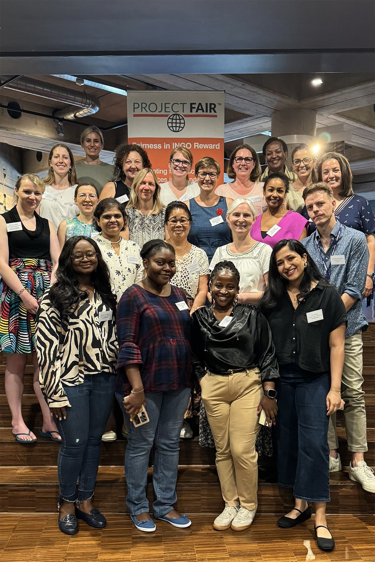 Attendees pose for a photo in front of a banner during the Project Fair Roundtable Meeting focused on INGO benefits.